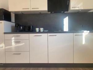 een keuken met witte kasten en een zwart aanrechtblad bij Appartementhaus Bad Salve in Hopfgarten im Brixental