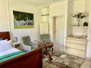 ein Schlafzimmer mit einem Bett, einem Tisch und einem Stuhl in der Unterkunft Cozy Cottage in idyllic greenery in Harkerville