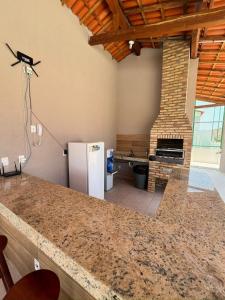 a kitchen with a refrigerator and a brick fireplace at Casa duplex em condomínio Parnaiba in Parnaíba