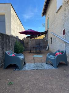 Saint-Maurice-lʼExilHome的庭院配有两把椅子、一张桌子和一把遮阳伞