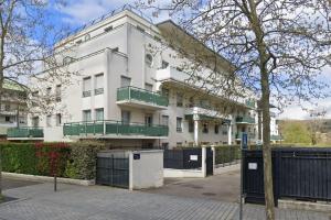 ein großes weißes Gebäude mit grünen Balkonen darauf in der Unterkunft Cosy Jolie T3 - Centre - Parking souterrain in Mantes-la-Jolie