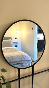 Schlafzimmer mit einem Bett und einem runden Spiegel in der Unterkunft Cosy Studio Steps From Beach in Weymouth