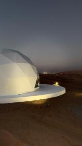 a white surfboard sitting on the beach at night at The mirage dome in Bidiyah