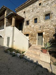 un edificio de piedra con una puerta y una escalera en Maison pure style provençale-jardin clôturé-4 pers, en Collorgues