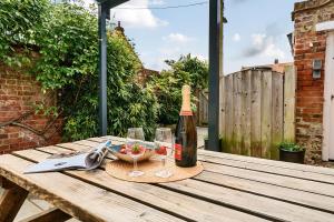 a bottle of wine and a bowl of fruit on a wooden table at Avocet Cottage in Brancaster