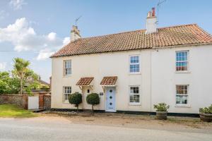 a white house with a blue door at Avocet Cottage in Brancaster
