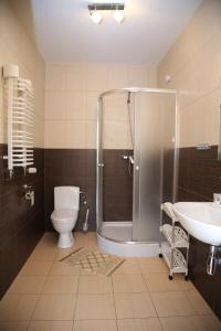 a bathroom with a shower and a toilet and a sink at Sanatorium Borkowo in Połczyn-Zdrój