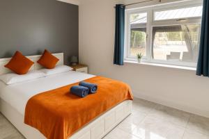 a bedroom with a bed with an orange blanket and a window at Countryside Retreat in Codicote