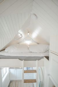 ein Hochbett in einem weißen Zimmer mit weißen Kissen in der Unterkunft Olenilsøya Mini Villa in Reine