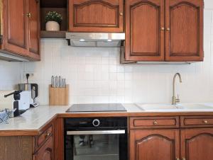 eine Küche mit Holzschränken und einem Herd mit Backofen in der Unterkunft LE CHESTER - Maison de charme en Provence avec piscine près de L'Isle-sur-la-Sorgue in Velleron