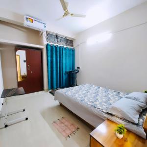 a bedroom with a bed and a blue curtain at The Mishing Room in Guwahati