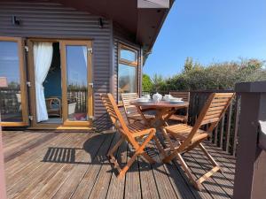 a wooden deck with a table and chairs on it at Lamorna in Penzance