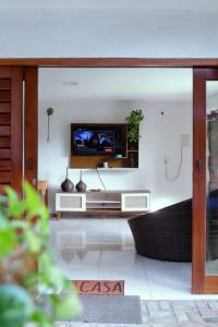 ein Wohnzimmer mit einem Fernseher an der Wand in der Unterkunft Casa da Cabana Guajiru in Trairi