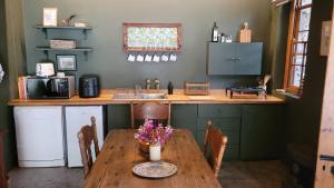 eine Küche mit einem Holztisch mit Blumen darauf in der Unterkunft Stone Cottage With Sea Views in Wilderness