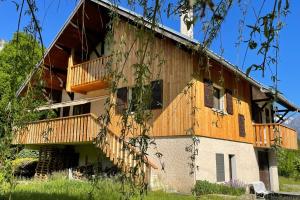 a building with a wooden deck on the side of it at Le Mas du Plan in Le Bourg-dʼOisans