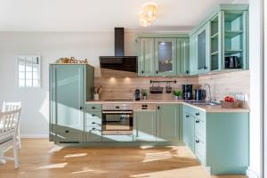 uma cozinha com armários verdes e um fogão em Panoramic Loft mit Meerblick em Sierksdorf