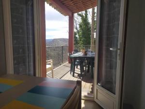 an open door to a balcony with a table on a deck at Le cheiron in Coursegoules