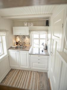 eine kleine Küche mit weißen Schränken und einer Spüle in der Unterkunft Olenilsøya Mini Villa in Reine + 23 Fotos