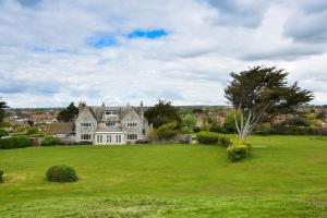 une grande maison dans un champ d'herbe verte dans l'établissement Florence House in Sussex, à Seaford
