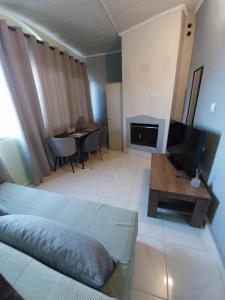 a room with a bed and a television and a table at Villa Artzie. Έξοχικο με τεράστιο εξωτερικό χώρο. in Nea Kalikratia