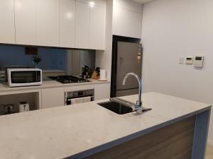 eine Küche mit Spüle und Kühlschrank in der Unterkunft Lumière Riverside One Bedroom Apartment In Ryde With Queen Bed and Free Parking Close to Train & Ferry & Cafes in Sydney