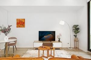 ein Wohnzimmer mit Sofa und Tisch in der Unterkunft Lumière Riverside One Bedroom Apartment In Ryde With Queen Bed and Free Parking Close to Train & Ferry & Cafes in Sydney