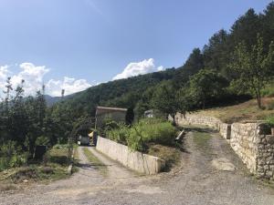 a dirt road with a stone wall next to a mountain at Gite du grand braquet in Puget-Théniers
