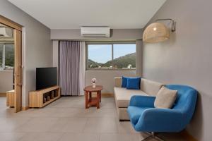 Una sala de estar con un sofá y un televisor. en Mercure Phuket Patong Journeyhub, en Patong Beach