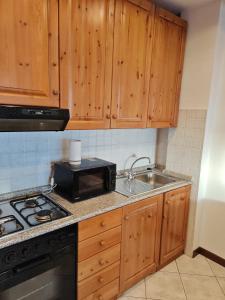 a kitchen with wooden cabinets and a sink and a microwave at La Baita del Sagittario in Prato Nevoso +15 photos
