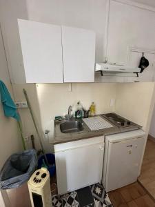 a small kitchen with white cabinets and a sink at Bright apartment, 5 minutes from Paris in Asnières-sur-Seine