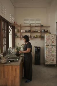 Una mujer parada en una cocina preparando comida. en a-mâze house, en Hue