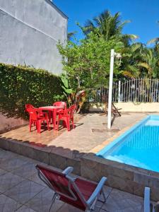 Eine Gruppe roter Stühle und ein Tisch neben einem Pool in der Unterkunft casa dos MORAIS in Angra dos Reis