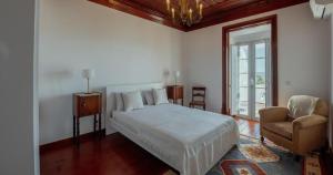 een slaapkamer met een bed, een stoel en een raam bij Ria Endless South - Barroca Village - Sítio da Fortaleza in Tavira