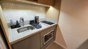 une petite cuisine avec un évier et une cuisinière dans l'établissement Refúgio Aconchegante na Cidade, à Campinas 16 autres photos