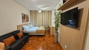 un salon avec un canapé, un lit et une télévision dans l'établissement Refúgio Aconchegante na Cidade, à Campinas