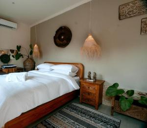 Schlafzimmer mit einem Bett mit weißer Bettwäsche und einem Tisch in der Unterkunft Villa Soluna Lovina in Lovina