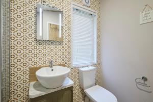 Un baño con lavabo, inodoro y espejo. en Lucky Lodge with Hot Tub, en York 21 fotos más