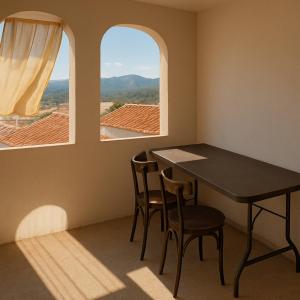 a table and chairs in a room with two windows at Comfortable house in Oliena