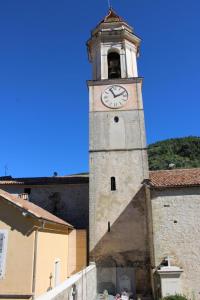 a tower with a clock on a building at L'ecureuil de luceram in Lucéram +5 photos