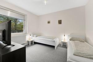 ein weißes Zimmer mit zwei Betten und einem Fernseher in der Unterkunft Apartment in Celle for Business Traveler in Celle