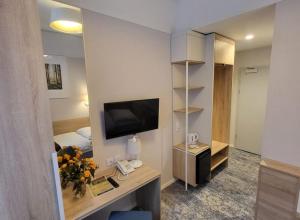 a room with a desk with a television and a bedroom at Sanatorium Gryf in Połczyn-Zdrój