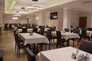 a dining room with white tables and black chairs at Sanatorium Gryf in Połczyn-Zdrój