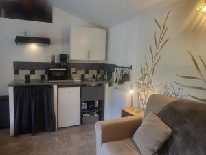 a living room with a couch and a kitchen at L'ombre du vent in Contes