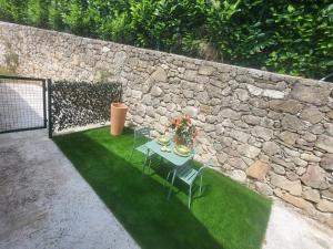 a table and chairs on the grass next to a stone wall at L'ombre du vent in Contes +6 photos