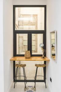 a window with a wooden table and two stools at NOMADIA en Plaza de la Constitucion 1 in Málaga