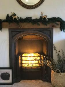 einen Kamin mit Weihnachtsdekoration darüber in der Unterkunft Beautiful Cottage nr Mendip Hills Private Parking in Chilcompton