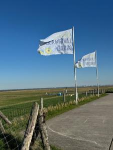 two flags on a fence next to a field at Ferienwohnung Reede 19 in Butjadingen