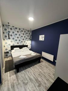 a bedroom with a bed and a blue wall at Margaréta Studió Apartman in Pusztavacs