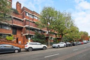 una fila di auto parcheggiate di fronte a un edificio di mattoni di Central London 2-Bed Flat - 6min to Victoria Station a Londra