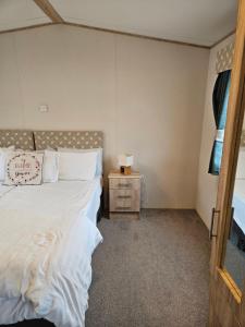 a bedroom with a bed and a night stand with a lamp at KMH Caravans at Flamingo Land in Kirby Misperton